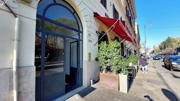 A building with a large arched entrance, a red awning, and a number "37" sign. - 4BNB - Marmorata Urban Nest (Rome)