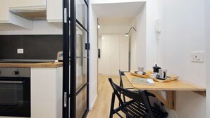 A modern kitchen with a built-in oven, a dining area with a wooden table and chairs, and a view into the adjacent room. - 4BNB - Marmorata Urban Nest (Rome)