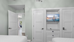 Habitación de hotel con dos camas, un televisor en la pared y vista al mar.