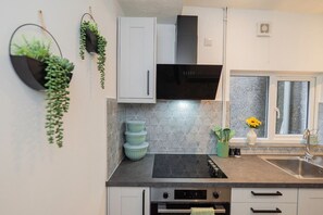 A kitchen with white cabinets, a black microwave, and a window with a view. - Modern house, sleeps up to 9 (Griffithstown)