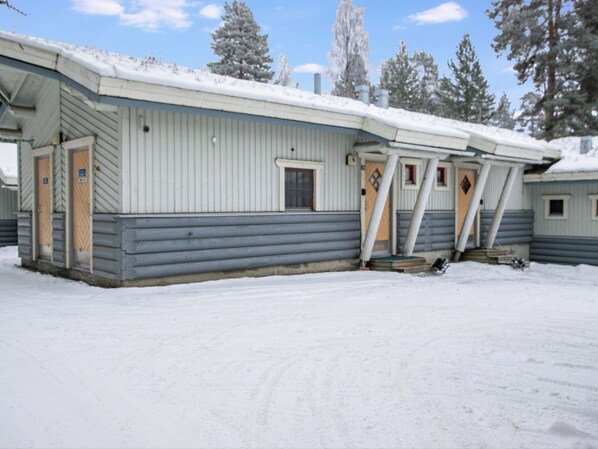 A row of cabins with a snow-covered roof and a wooden exterior.