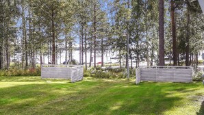 Un espacio al aire libre con césped, bancos de metal y árboles altos.