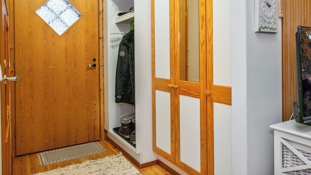 Ein Flur mit Holztüren, einem Kleiderständer und einer Uhr an der Wand.