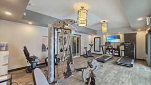 Een fitnessruimte met cardioapparatuur, krachtapparaten en een loopband.