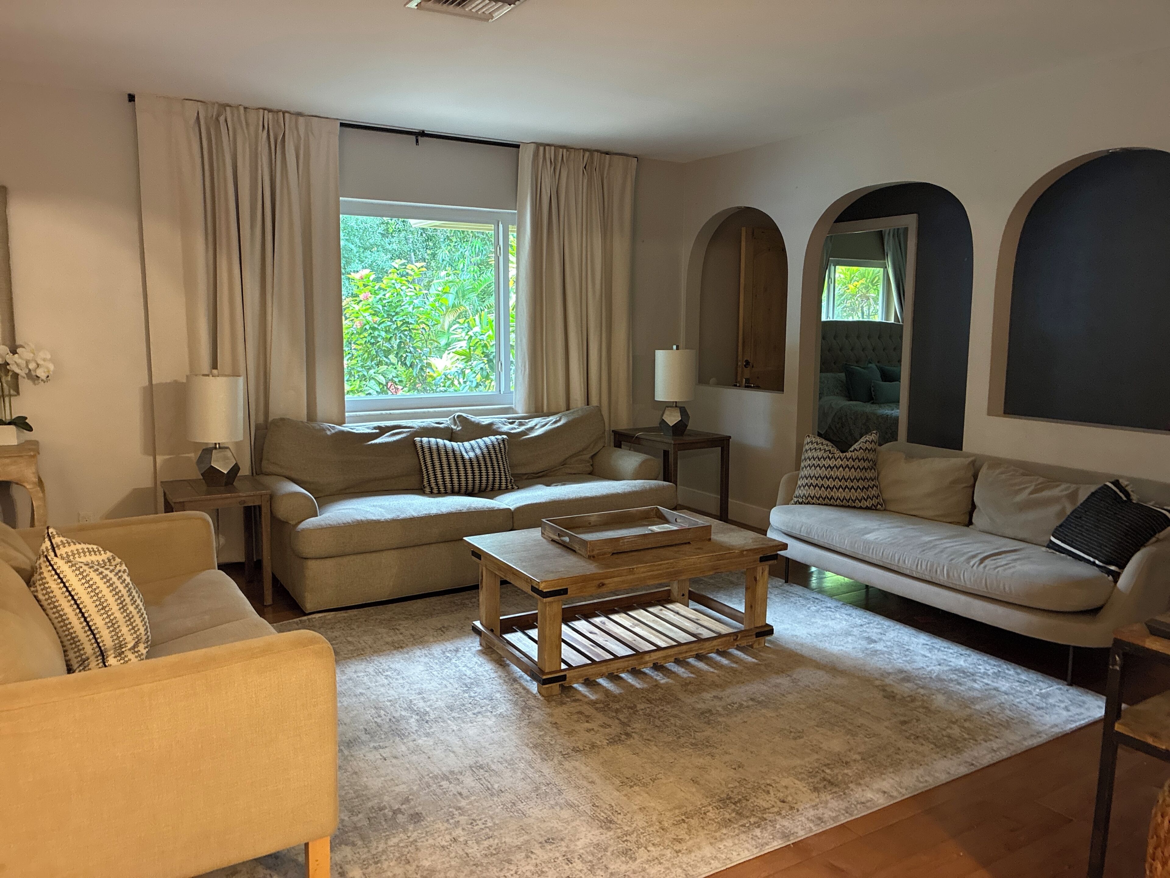 A living room with two sofas, a coffee table, and a window with curtains.