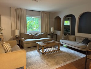 Ein Wohnzimmer mit zwei Sofas, einem Couchtisch und einem Fenster mit Vorhängen.