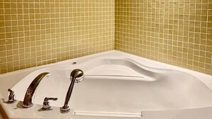 A bathroom with a large bathtub, tiled walls, and a wooden trim around the ceiling.