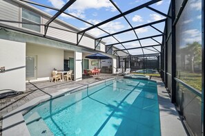 Ein Schwimmbad mit überdachter Terrasse, Sitzgelegenheiten im Freien und Blick auf die umliegende Landschaft.