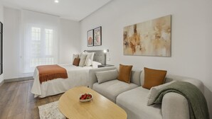 Un dormitorio moderno con cama, sofá, una mesita de centro y un cuadro en la pared.