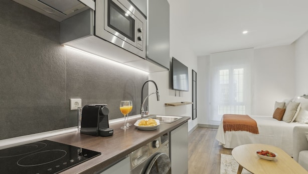 Una cocina compacta equipada con microondas, cafetera y lavamanos.