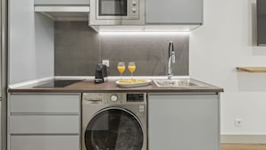Cocina compacta con microondas, lavabo y lavadora.