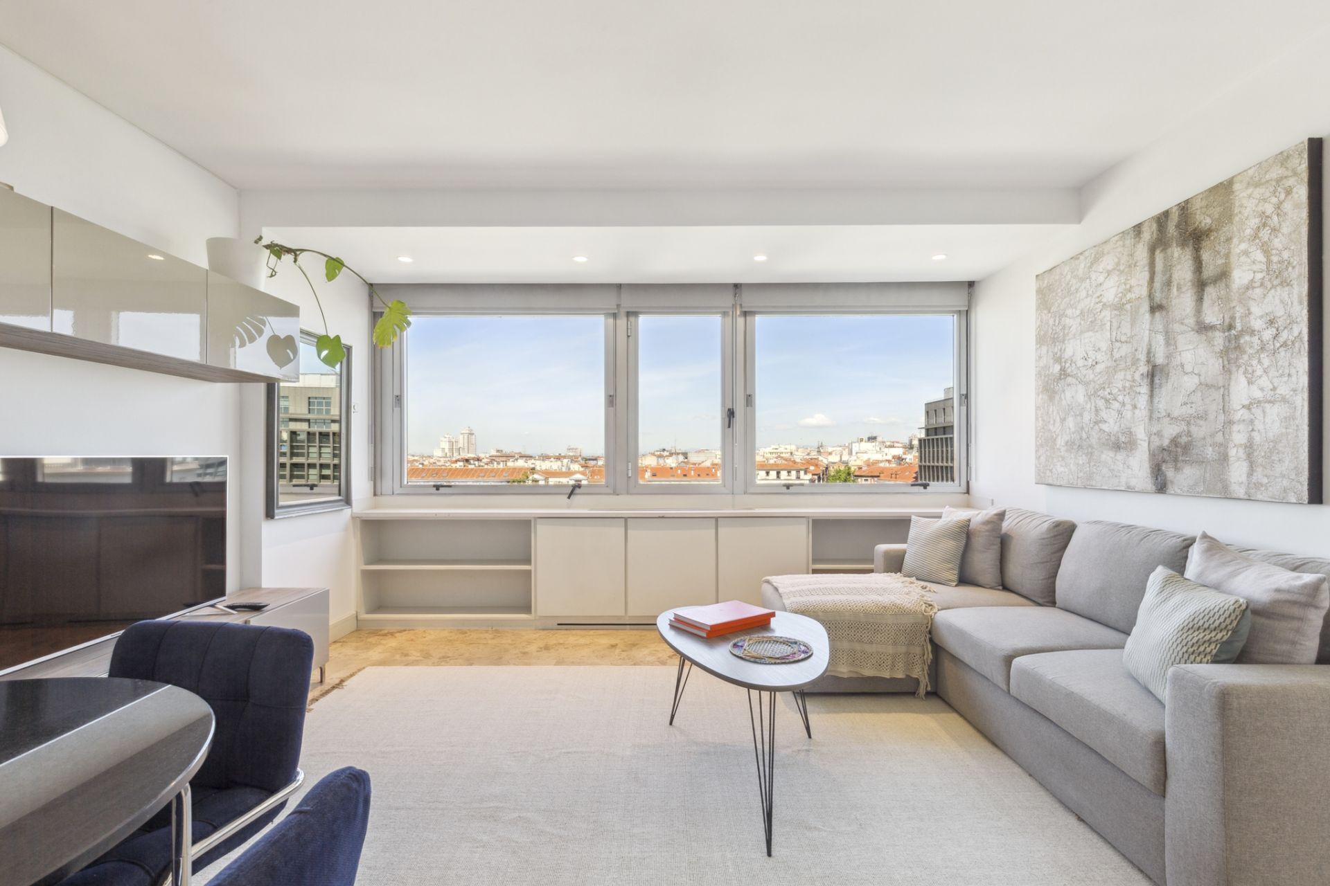 A modern living room with a sofa, a small table, and a TV.