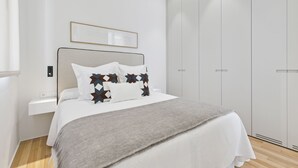 Ein modernes Schlafzimmer mit Bett, Nachttisch, Kleiderschrank und einem gerahmten Bild an der Wand.