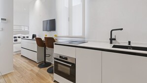 Eine moderne Küche mit einer großen Kochinsel, einem eingebauten Backofen und einem flachbildfernseher, der über der Insel angebracht ist.