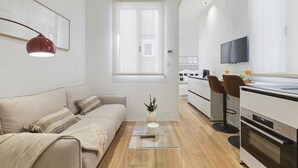 Ein modernes, gut beleuchtetes Wohnzimmer mit einer Couch, einem Couchtisch und einem Fernseher im Hintergrund.