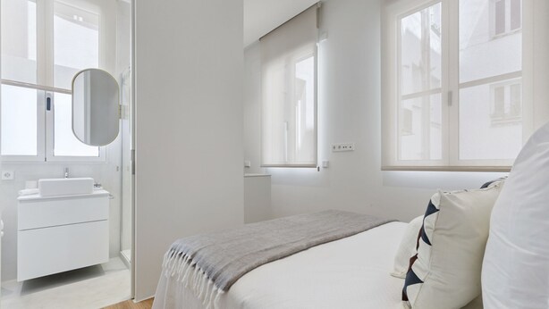 Ein modernes Schlafzimmer mit Bett, Nachttisch und einem großen Fenster.