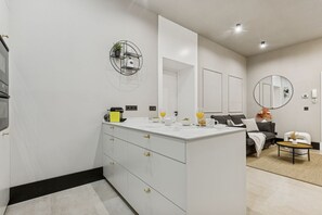 Un baño moderno con un tocador blanco, un espejo grande y un espejo redondo en la pared.