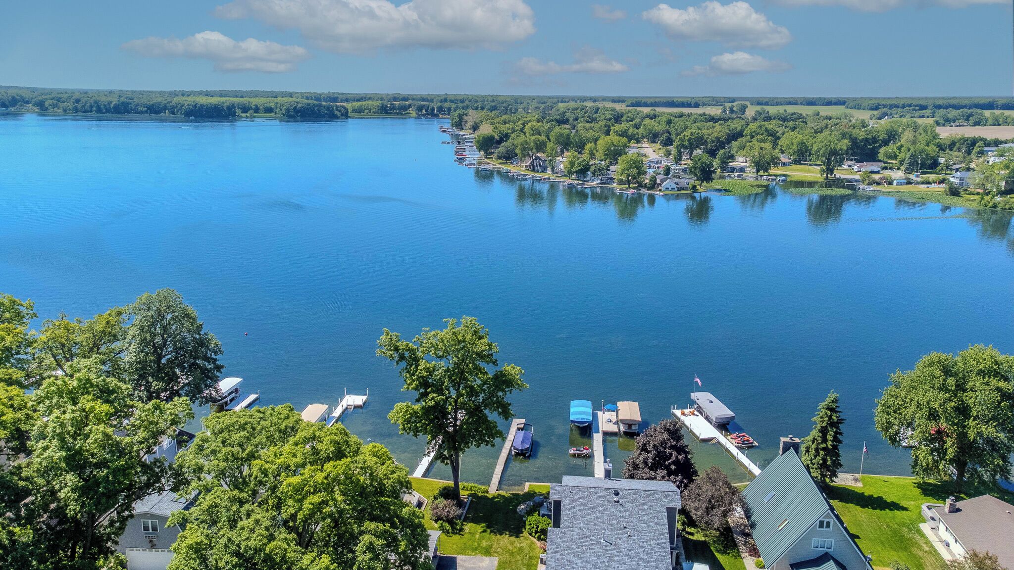 A lake with boats docked, surrounded by trees and houses.