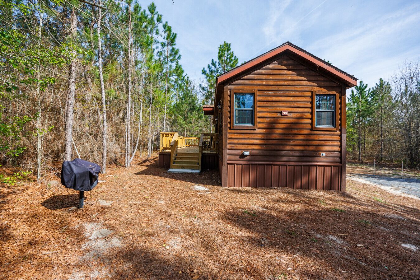 Eine Holzhütte mit einer Terrasse, umgeben von Bäumen.