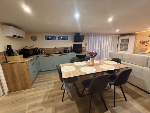 A modern kitchen with a dining area, featuring a wooden table, chairs, and a sofa. - 15 minutes from Futuroscope! Beautiful two-bedroom house, ideal for families (Naintré)
