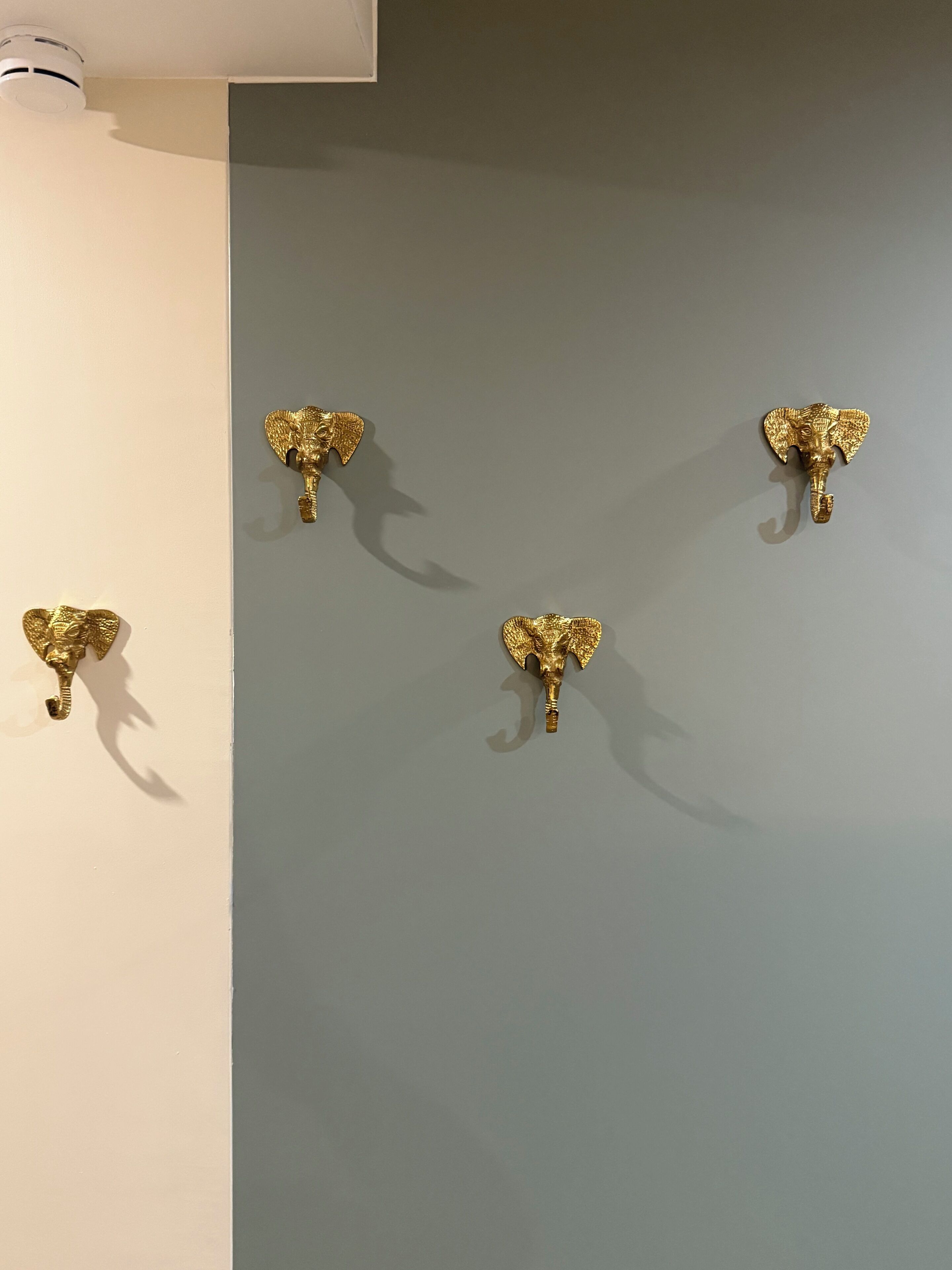 Un muro con quattro ganci a forma di elefante dorati.