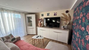 A living room with a sofa, a coffee table, a TV, and a cabinet. - 15 minutes from Futuroscope! Lovely two-bedroom house ideal for families (Naintré)