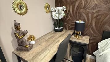 A modern dining area with a wooden table, black chairs, and decorative items including golden sunburst mirrors and white orchids.