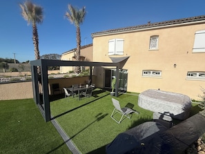 A patio area with a table and chairs, a covered seating area, and a stone barbecue grill. - 15 minutes from Futuroscope! Lovely two-bedroom house ideal for families (Naintré)