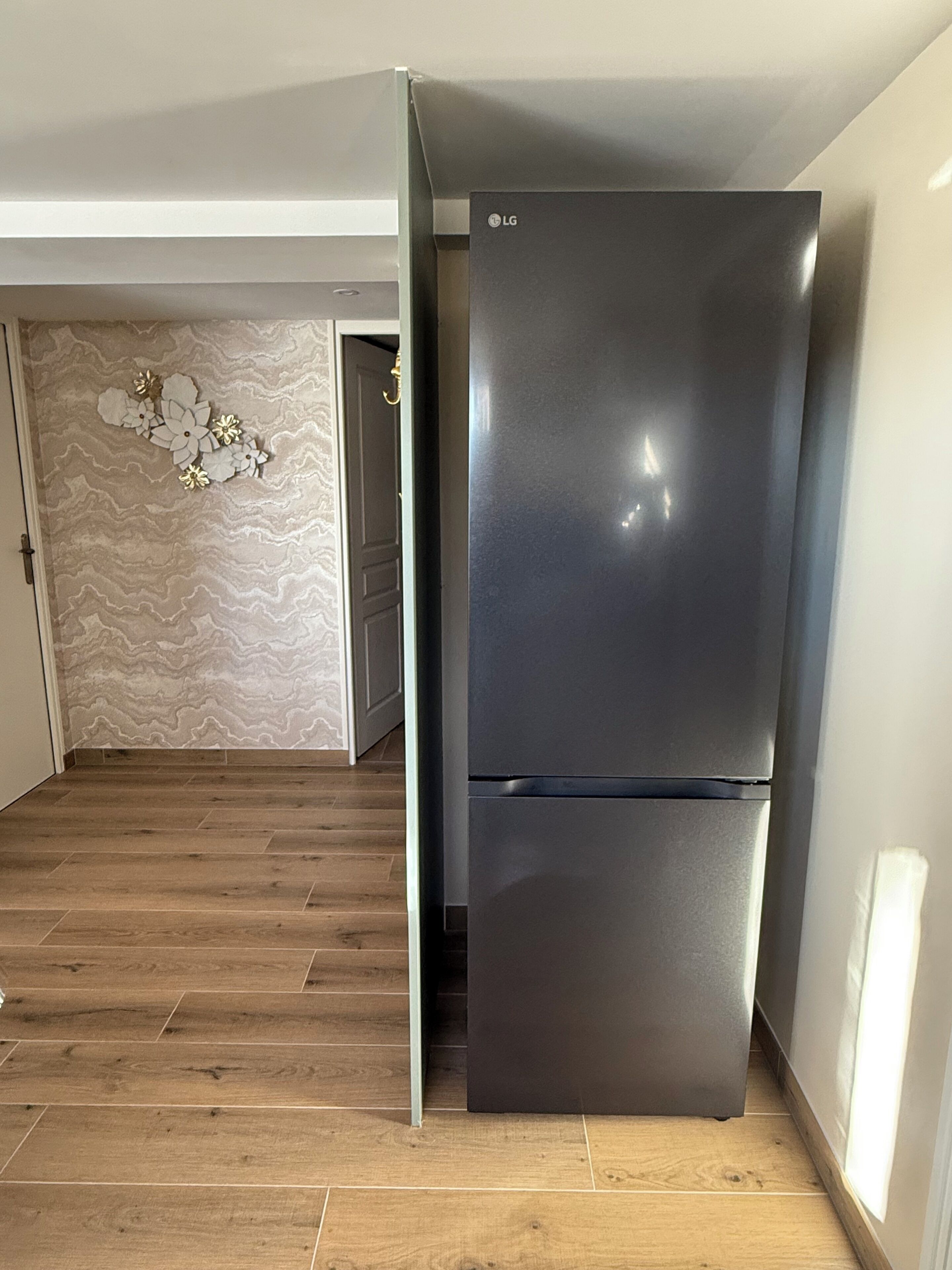 Eine moderne Küche mit einem schwarzen LG-Kühlschrank, Holzböden und einer Wand mit einem floralen Muster.