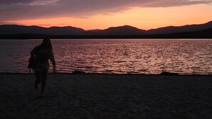 A beach scene with a person walking along the shore. - Luxury Roxbury Pond Lakefront (Roxbury)