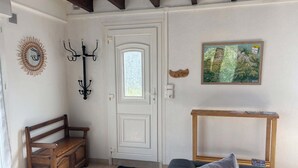 Une pièce comprenant un banc en bois, un porte-manteau, une porte, une console et un tableau encadré accroché au mur.