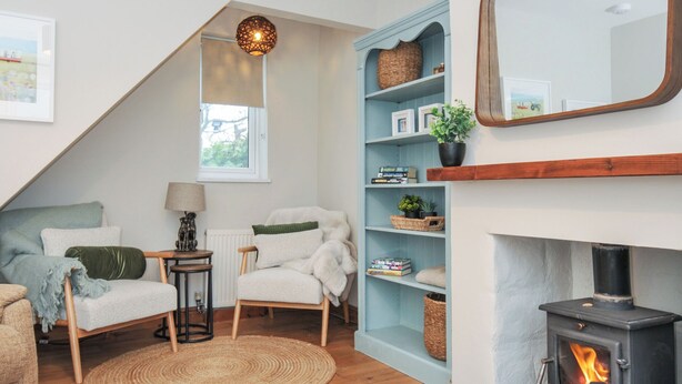 A cozy living room with a fireplace, a blue shelving unit, a round woven rug, and a hanging light fixture. - 4 Polgrain Turning (Bodmin)