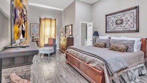 A bedroom with a large bed, a desk, a chair, and a TV. - Southern Sisters Retreat - The Lisa: Stylish, Cozy, Near MSU, Fire Pit + Grill (Starkville)