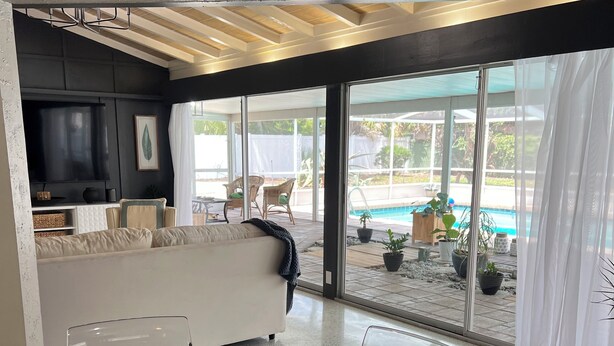 A modern living room with a glass dining table, a sofa, and a TV. - Modern house with pool near Downtown (Lakeland)