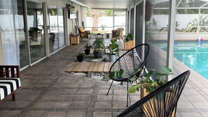 A covered patio with tiled flooring, outdoor furniture, and a pool. - Modern house with pool near Downtown (Lakeland)