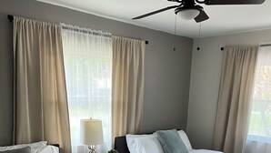 A hotel room with two beds, a ceiling fan, a nightstand with a lamp, and a view of the outdoors. - Modern house with pool near Downtown (Lakeland)