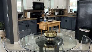 A modern kitchen with white cabinets, a black refrigerator, and a glass dining table. - Modern house with pool near Downtown (Lakeland)
