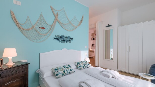 A bedroom with a bed, white headboard, and a nightstand with a lamp. - Mobilehome in Porlezza am Luganersee (Porlezza)
