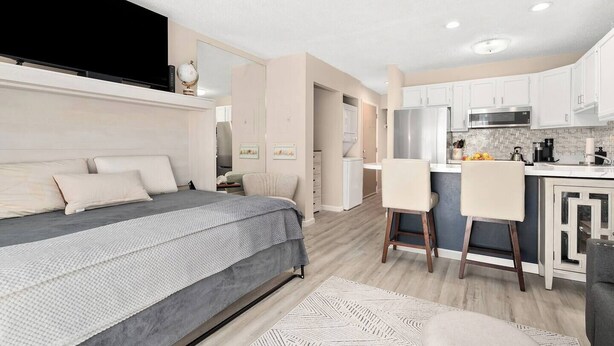 Un dormitorio moderno con una cama grande, un escritorio y una kitchenette.