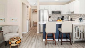 Una cocina moderna con armarios blancos, electrodomésticos de acero inoxidable y una isla central con taburetes de bar.