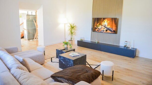 A modern living room with a fireplace, a sofa set, a coffee table, and a television mounted on the wall.
