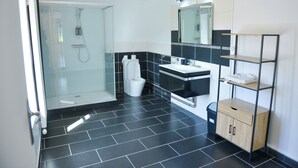 A modern bathroom with a glass shower enclosure, a toilet, a sink, and a wooden cabinet.