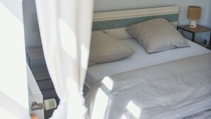 A bed with pillows, a nightstand with a lamp, and a partially visible door.