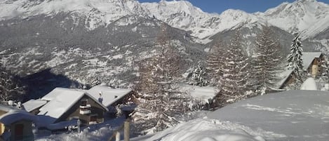 A snow-covered mountain landscape with a chalet-style building in the foreground.