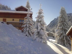 Ein schneebedecktes Berghotel mit Holzfassade und einem Balkon mit Blick auf die verschneite Landschaft.