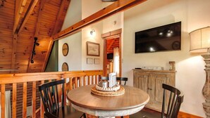 Zona pranzo con tavolo rotondo, sedie e soffitto in legno.