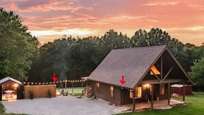 Una baita di tronchi con un portico, un piccolo deposito e un’area coperta decorata con luci a stringa.