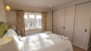 Une chambre d’hôtel avec un grand lit, une fenêtre avec des rideaux, un radiateur et une armoire.