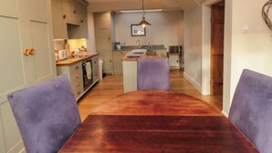 Une cuisine compacte avec un îlot central, une table en bois et des chaises violettes.
