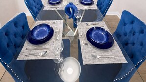 A dining room with a glass table, blue upholstered chairs, and a white pendant light. - 5-STAR Sarasota Stay Luxur 2BR/2BA (Sarasota)